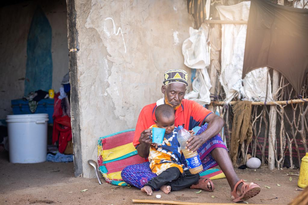 A father gives his thirsty son water in Lagdera, Garissa County.